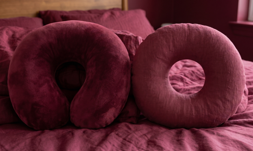 Comparison between a velvet U-shaped neck pillow and a round donut piercing pillow with an ear hole.