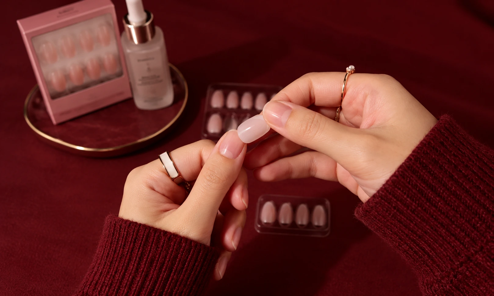 Applying a nude-pink press-on nail at home.